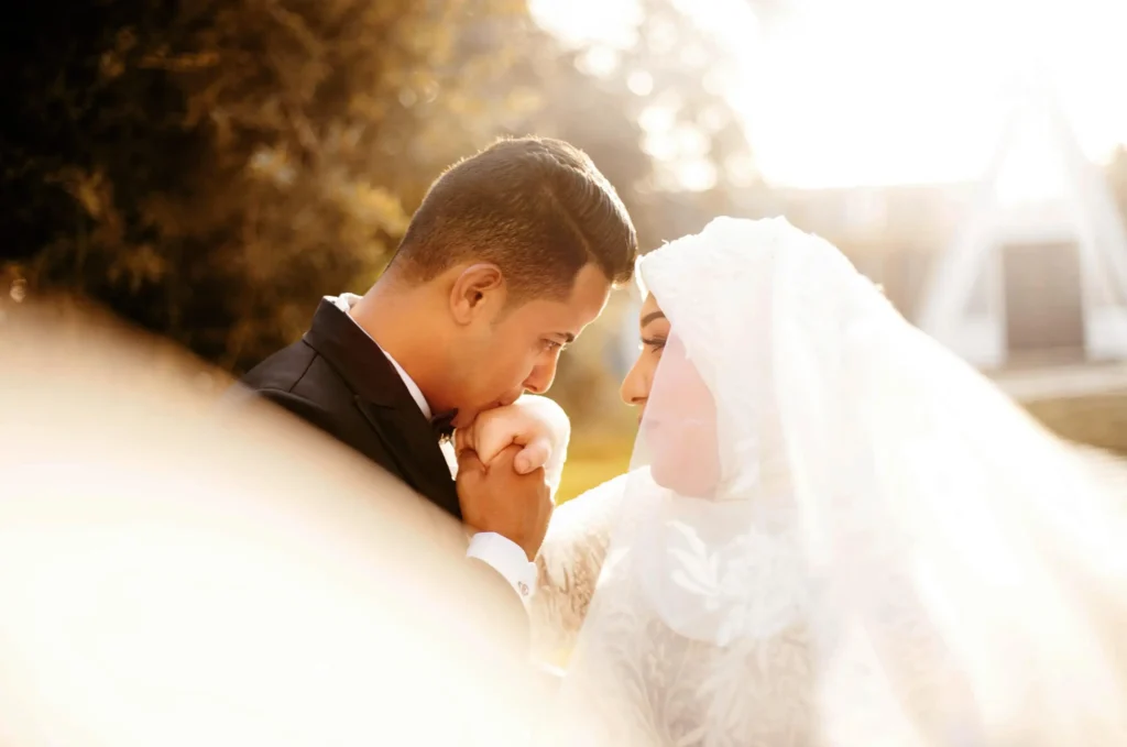 Wedding photography of a groom kissing his bride's hand during an outdoor ceremony in Dubai