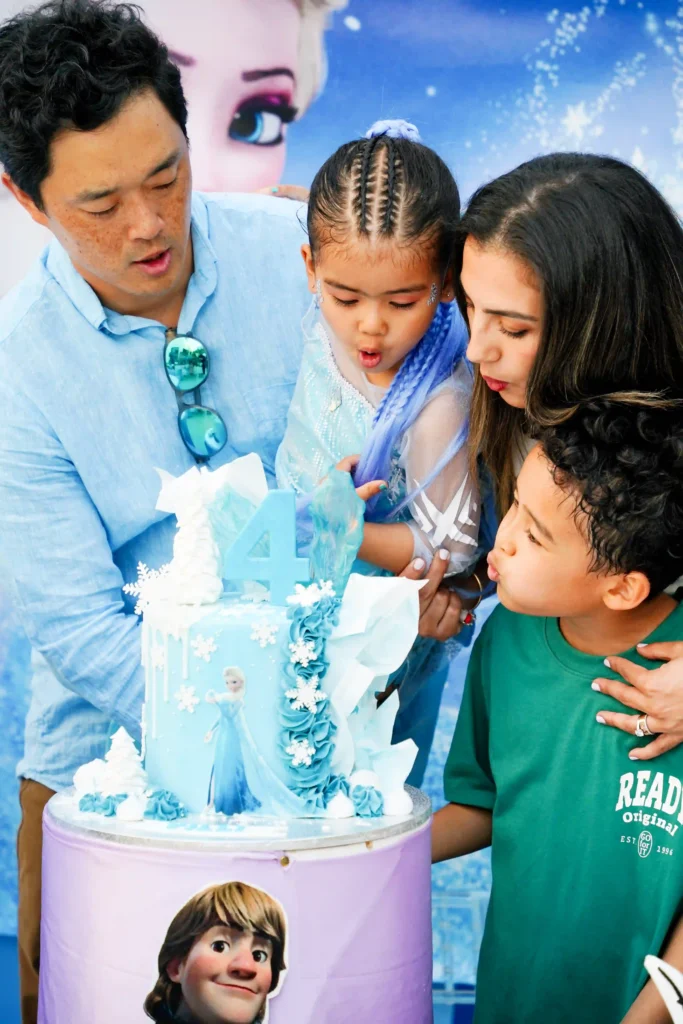 A family together blowing out candles on a Frozen-themed birthday cake, captured by a professional birthday photographer in Dubai.